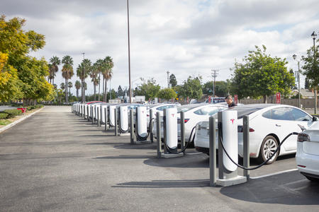 Line of white cars charging via electric charging points