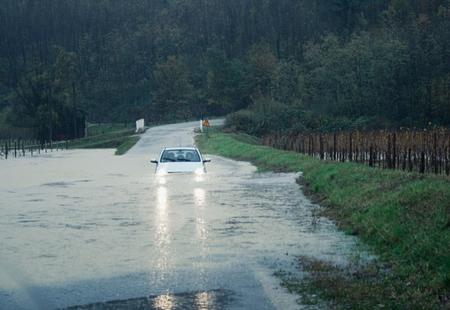 Flooded road in Slovenia with car half submerged