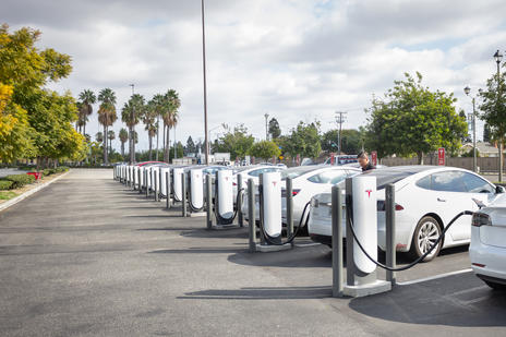 Line of white cars charging via electric charging points